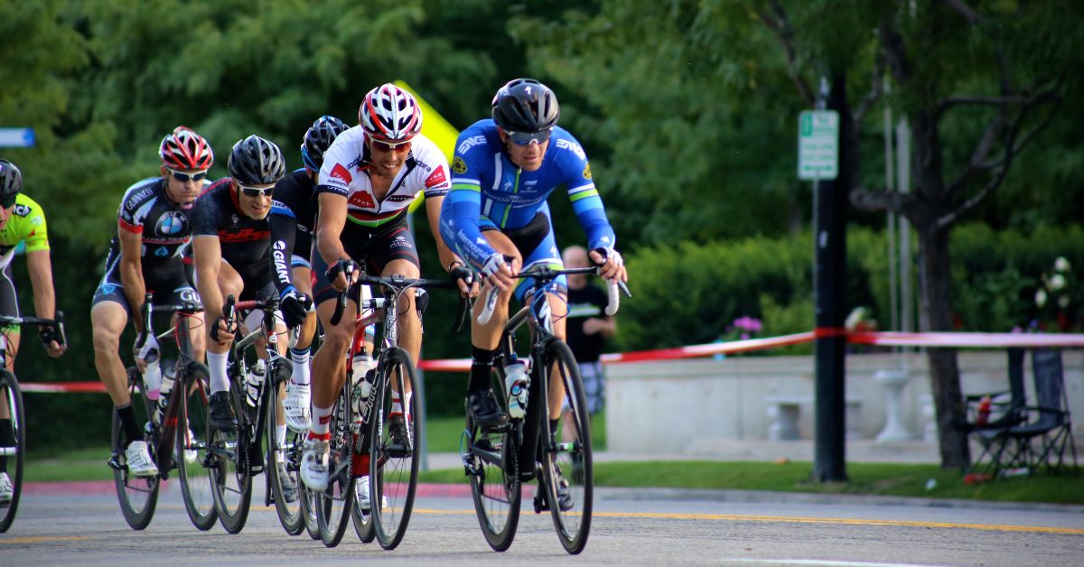 a group of cyclists in racing attire riding in the middle of a roped off street