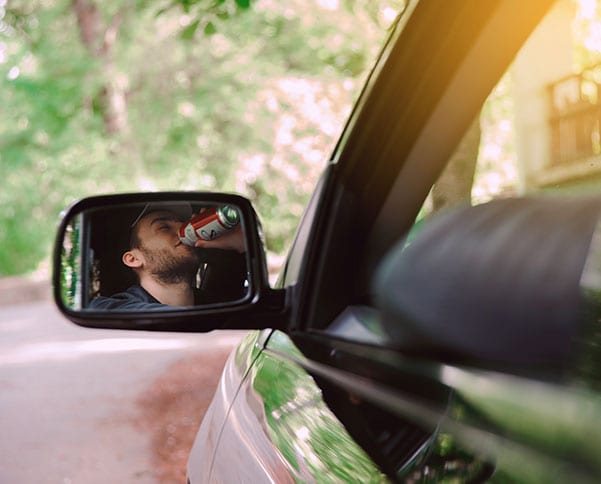 Man drinking a canned drink while in a car