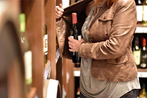 woman shoplifting a bottle of wine