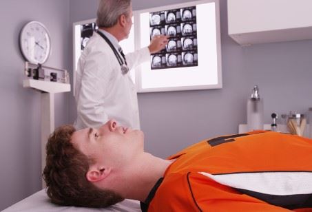 young man laying on doctors table with brain scans in background